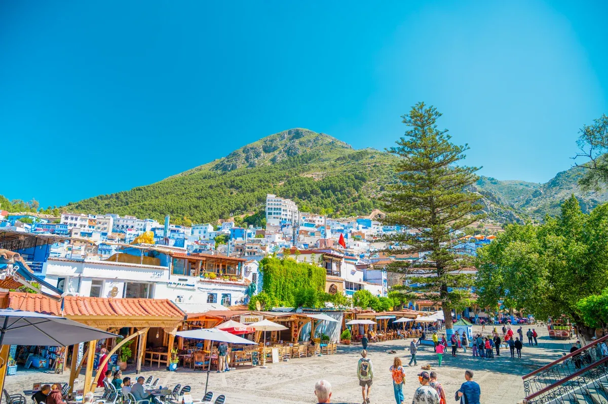 Chefchaouen square with the Rif mountain behind the blue town on a Morocco tour package, Chefchaouen, Morocco
