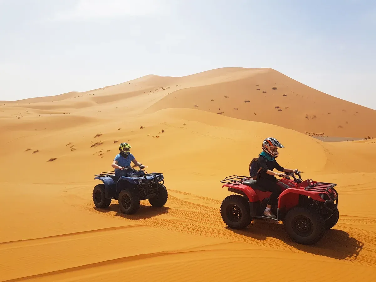 Two quad bikes crossing a dune at Erg Chebbi in Merzouga on a Morocco tour package, Erg Chebbi dunes, Merzouga, Morocco